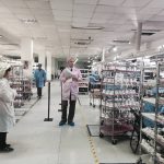 Goodada inspector conducting a quality inspection inside a Chinese manufacturing facility, reviewing products on the production line alongside factory staff.