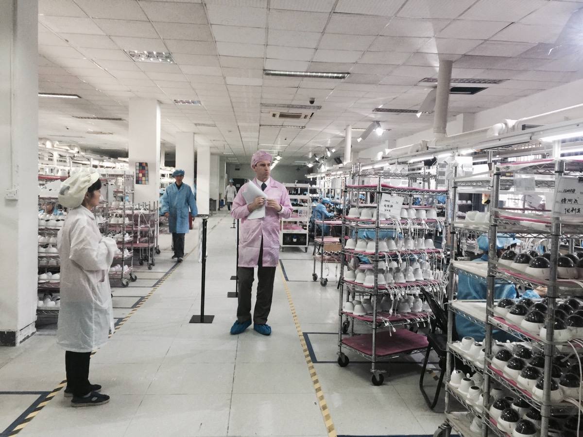 Goodada inspector conducting a quality inspection inside a Chinese manufacturing facility, reviewing products on the production line alongside factory staff.